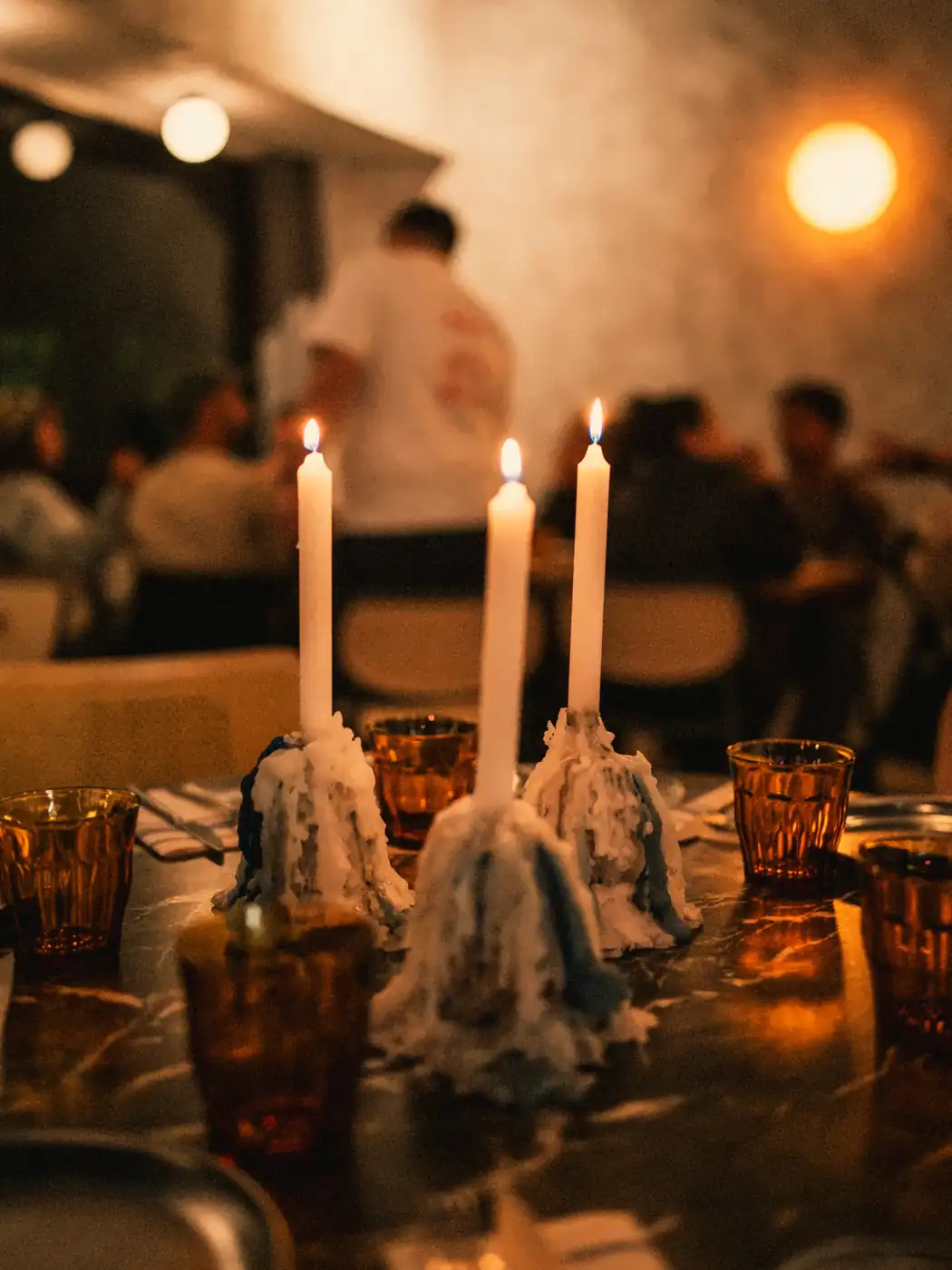 La sala de 95 llena una noche, con velas en candelabro sobre las mesas de mármol negro