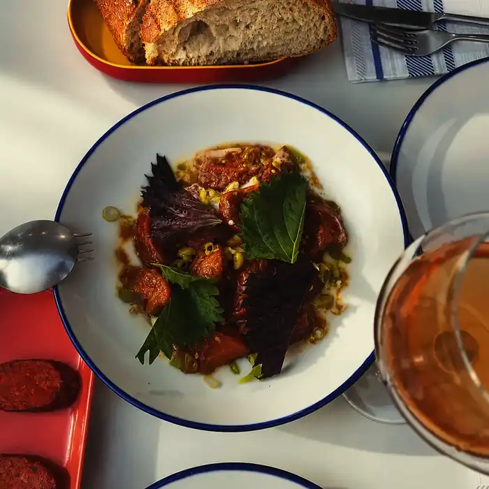Tomate asado con ajo blanco de coco en plato blanco de borde azul